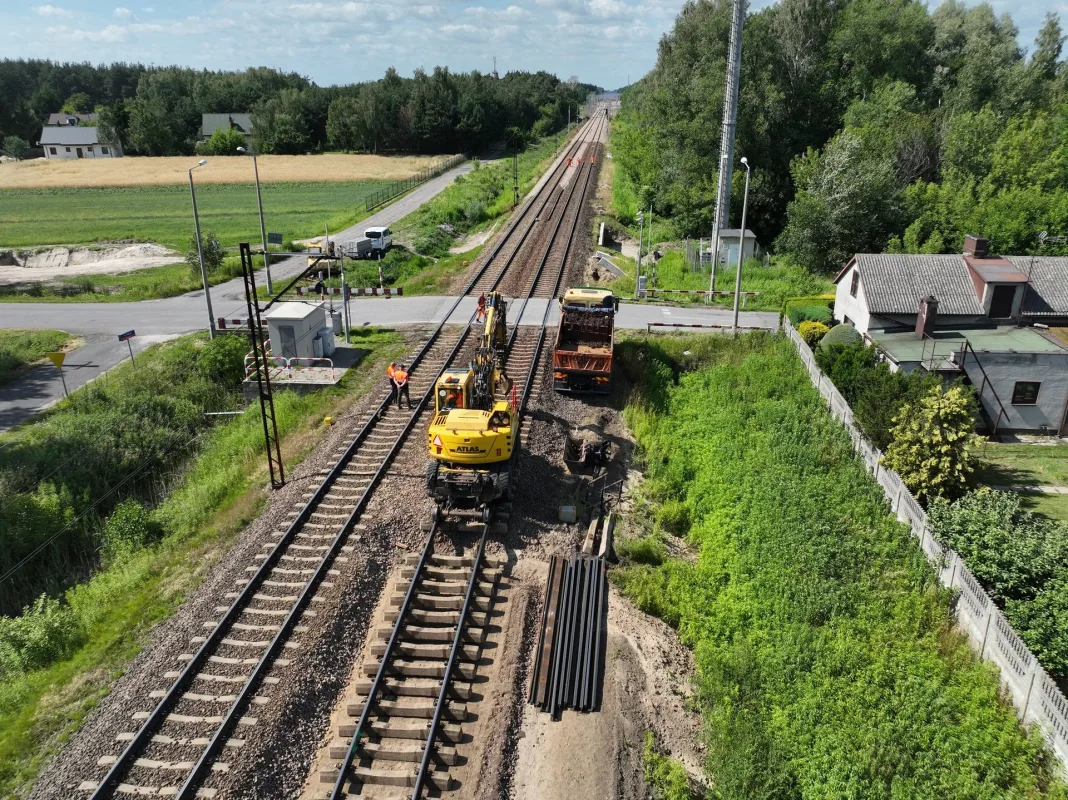 wykonawcy remontują tor w Bełchowie, widać maszyny budowlane – opis sytuacji na zdjęciu: pokazani są pracownicy (wykonawcy) prowadzący remont toru kolejowego w Bełchowie; na fotografii widoczne są maszyny budowlane.