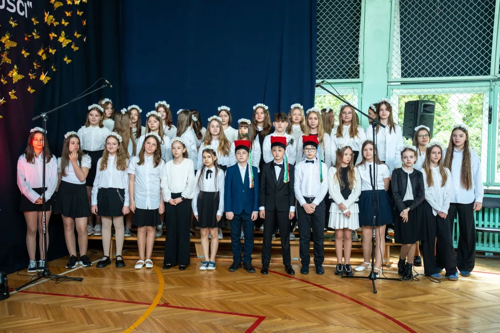Występ artystyczny uczniów podczas oficjalnej akademii z okazji 110-lecia SP 2 w Skierniewicach, na scenie baner jubileuszowy.