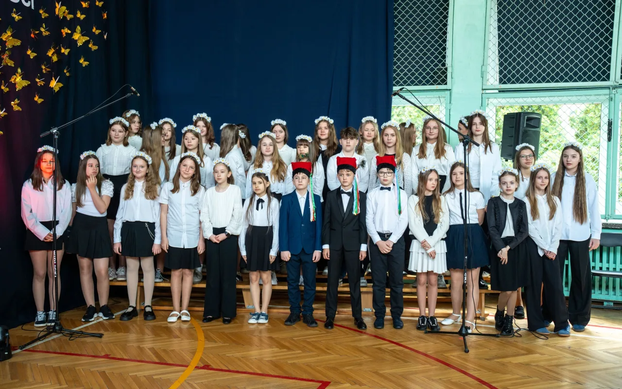 Występ artystyczny uczniów podczas oficjalnej akademii z okazji 110-lecia SP 2 w Skierniewicach, na scenie baner jubileuszowy.