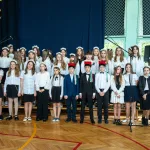 Występ artystyczny uczniów podczas oficjalnej akademii z okazji 110-lecia SP 2 w Skierniewicach, na scenie baner jubileuszowy.
