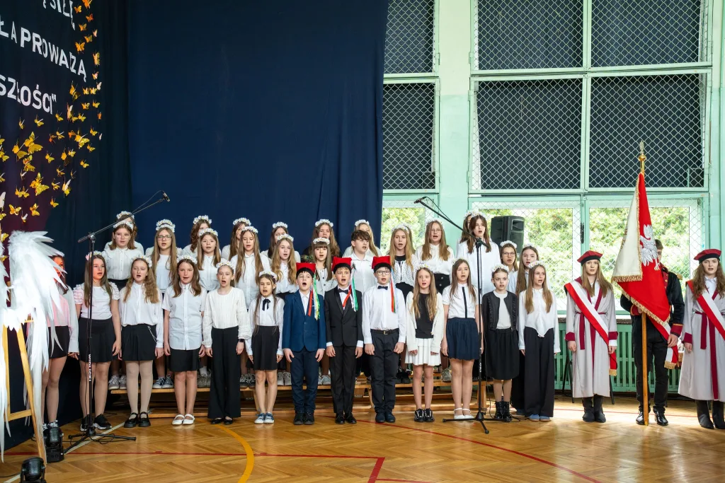 Występ artystyczny uczniów podczas oficjalnej akademii z okazji 110-lecia SP 2 w Skierniewicach, na scenie baner jubileuszowy.