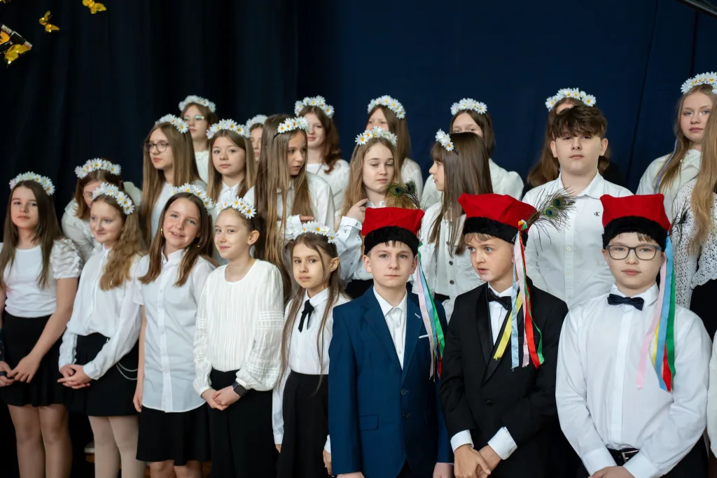 Występ artystyczny uczniów podczas oficjalnej akademii z okazji 110-lecia SP 2 w Skierniewicach, na scenie baner jubileuszowy.