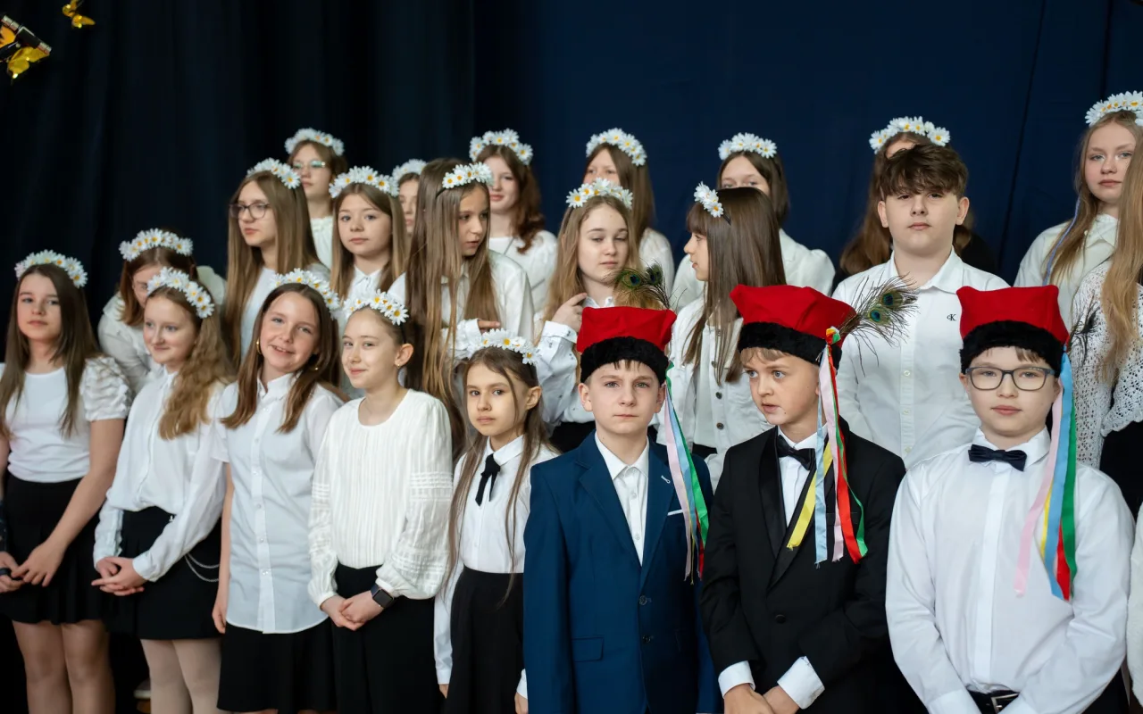 Występ artystyczny uczniów podczas oficjalnej akademii z okazji 110-lecia SP 2 w Skierniewicach, na scenie baner jubileuszowy.