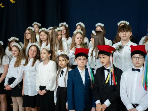 Występ artystyczny uczniów podczas oficjalnej akademii z okazji 110-lecia SP 2 w Skierniewicach, na scenie baner jubileuszowy.