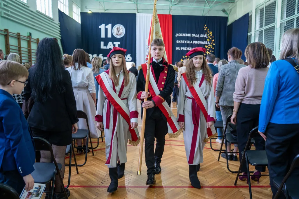Występ artystyczny uczniów podczas oficjalnej akademii z okazji 110-lecia SP 2 w Skierniewicach, na scenie baner jubileuszowy.