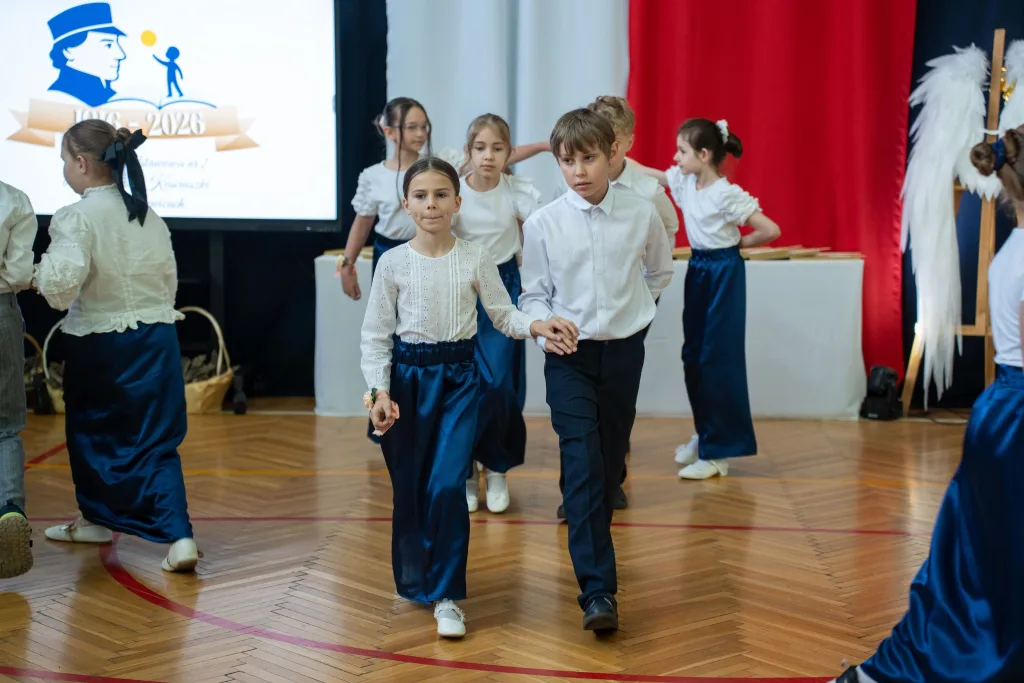 Występ artystyczny uczniów podczas oficjalnej akademii z okazji 110-lecia SP 2 w Skierniewicach, na scenie baner jubileuszowy.