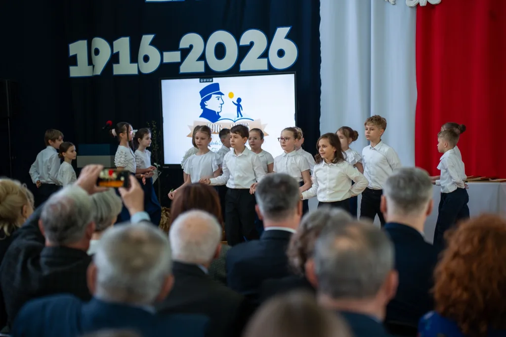 Występ artystyczny uczniów podczas oficjalnej akademii z okazji 110-lecia SP 2 w Skierniewicach, na scenie baner jubileuszowy.