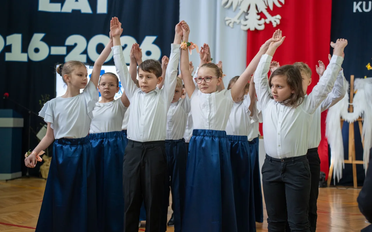 Występ artystyczny uczniów podczas oficjalnej akademii z okazji 110-lecia SP 2 w Skierniewicach, na scenie baner jubileuszowy.