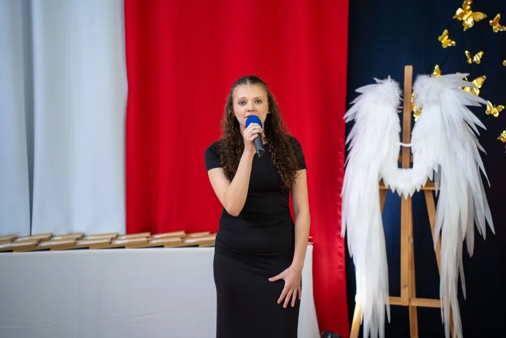 Występ artystyczny uczniów podczas oficjalnej akademii z okazji 110-lecia SP 2 w Skierniewicach, na scenie baner jubileuszowy.