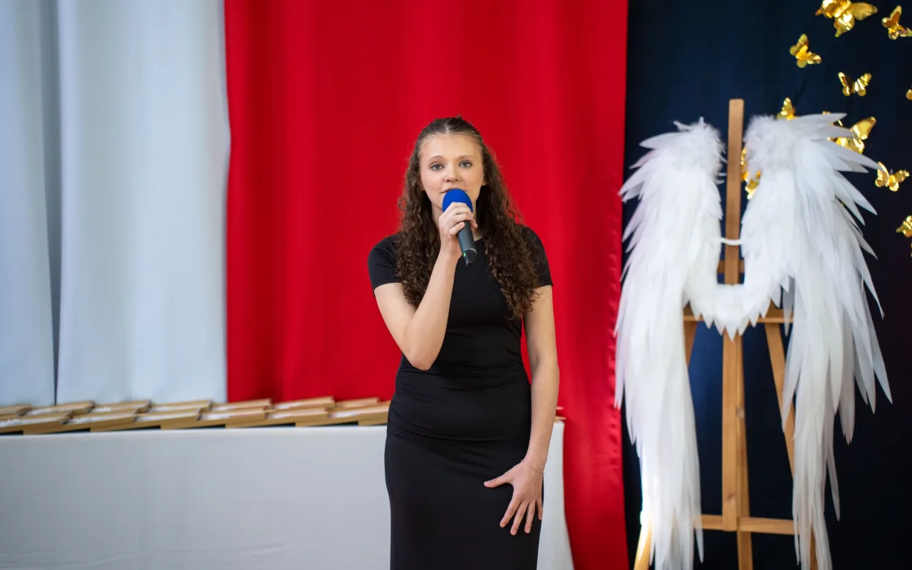 Występ artystyczny uczniów podczas oficjalnej akademii z okazji 110-lecia SP 2 w Skierniewicach, na scenie baner jubileuszowy.