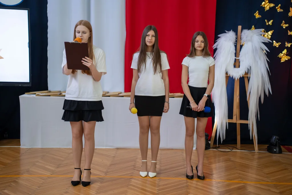 Występ artystyczny uczniów podczas oficjalnej akademii z okazji 110-lecia SP 2 w Skierniewicach, na scenie baner jubileuszowy.