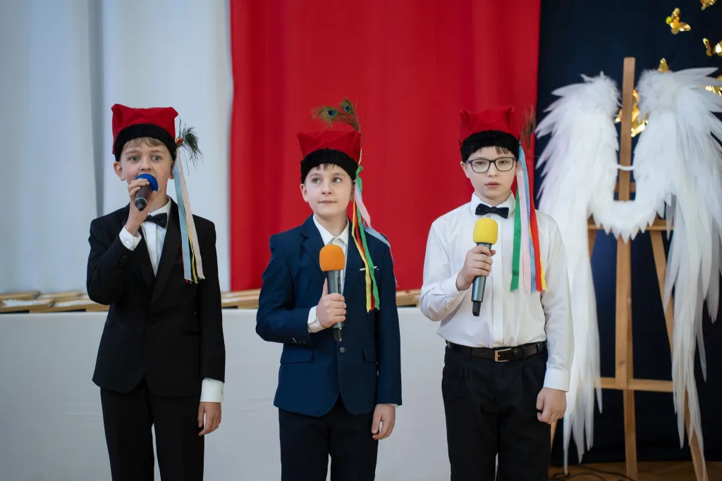 Występ artystyczny uczniów podczas oficjalnej akademii z okazji 110-lecia SP 2 w Skierniewicach, na scenie baner jubileuszowy.