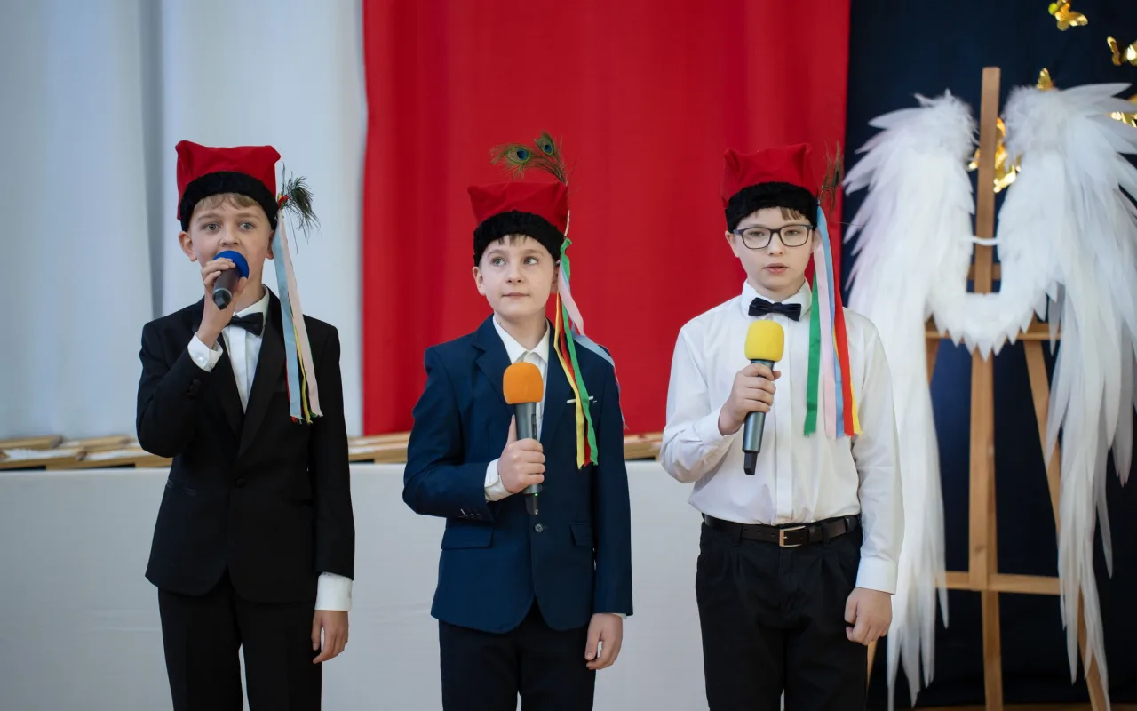 Występ artystyczny uczniów podczas oficjalnej akademii z okazji 110-lecia SP 2 w Skierniewicach, na scenie baner jubileuszowy.