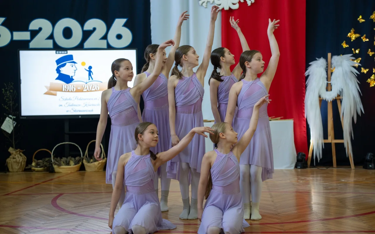 Występ artystyczny uczniów podczas oficjalnej akademii z okazji 110-lecia SP 2 w Skierniewicach, na scenie baner jubileuszowy.