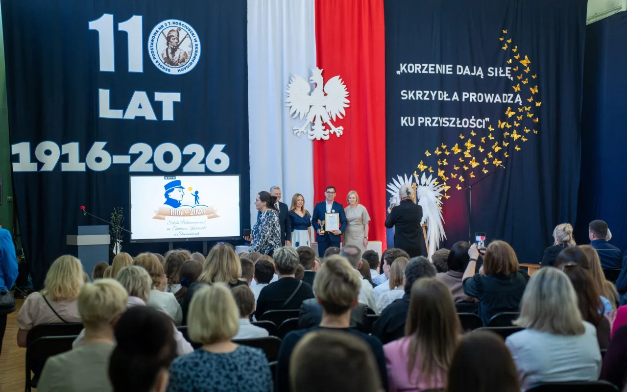 Występ artystyczny uczniów podczas oficjalnej akademii z okazji 110-lecia SP 2 w Skierniewicach, na scenie baner jubileuszowy.