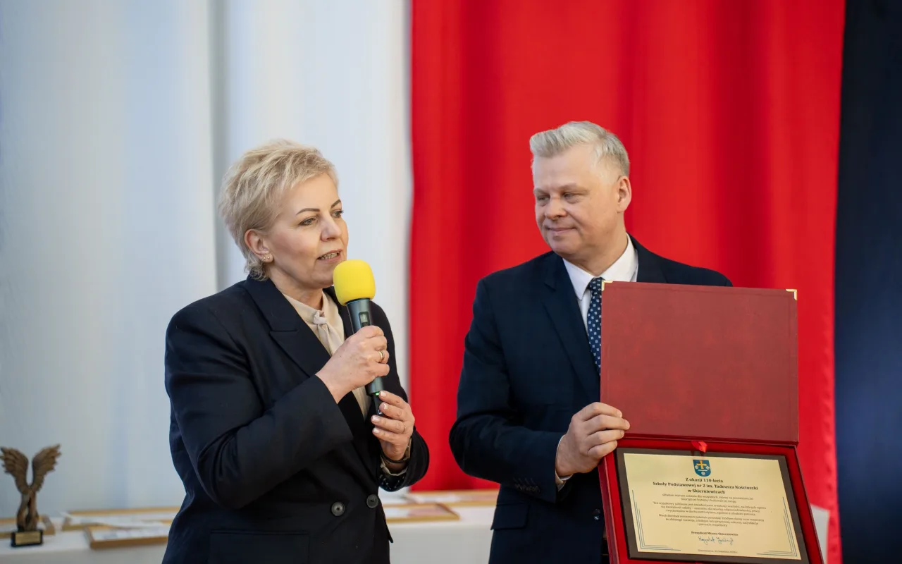 Występ artystyczny uczniów podczas oficjalnej akademii z okazji 110-lecia SP 2 w Skierniewicach, na scenie baner jubileuszowy.