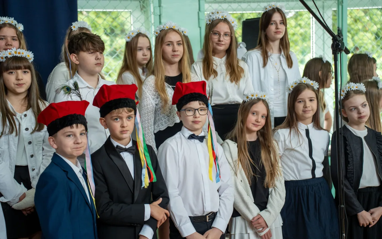 Występ artystyczny uczniów podczas oficjalnej akademii z okazji 110-lecia SP 2 w Skierniewicach, na scenie baner jubileuszowy.