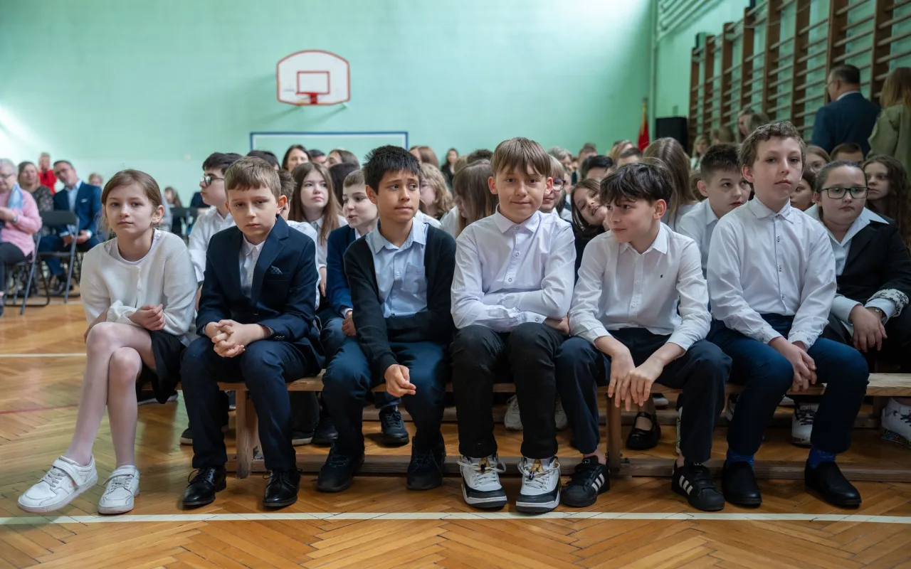 Występ artystyczny uczniów podczas oficjalnej akademii z okazji 110-lecia SP 2 w Skierniewicach, na scenie baner jubileuszowy.