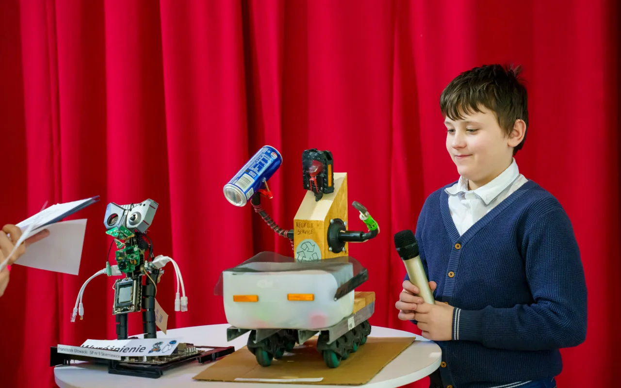 Uczeń prezentuje robota z materiałów recyklingowych podczas V Powiatowego Konkursu Technicznego w Skierniewicach