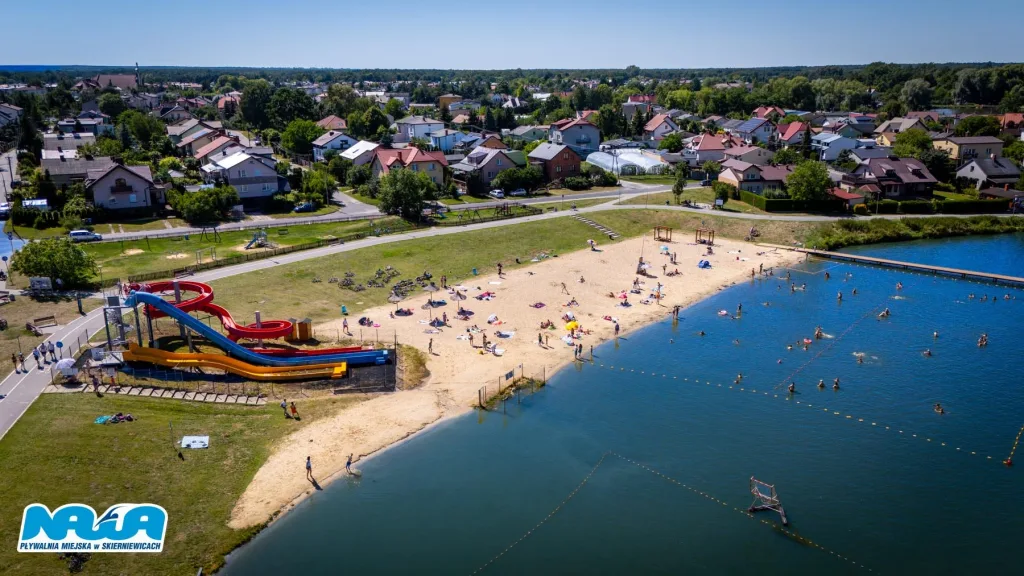 Zalew Zadębie w Skierniewicach z plażą, zjeżdżalniami wodnymi i osobami kąpiącymi się w upalny dzień. Gdzie nad wodę Skierniewice